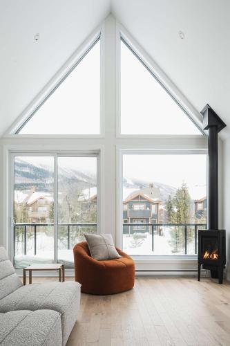 a living room with a large window and a couch at Villas Perspectives Spa and Mountain in Beaupré