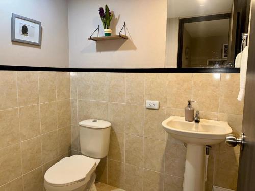 a bathroom with a toilet and a sink at Apartaestudios - Torre de Cali in Cali