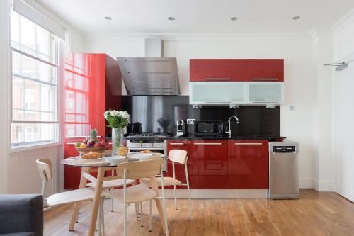 a kitchen with red cabinets and a table with chairs at Modern Carnaby Soho 1BR Apartment with AC in London