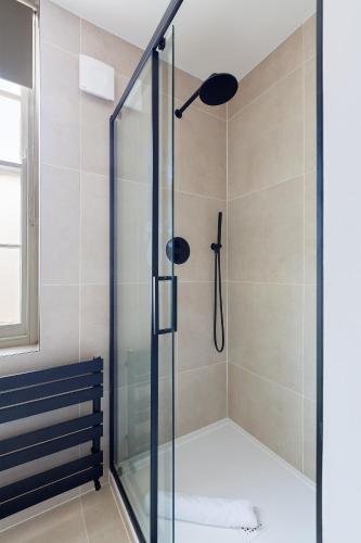a shower with a glass door in a bathroom at Modern Carnaby Soho 1BR Apartment with AC in London