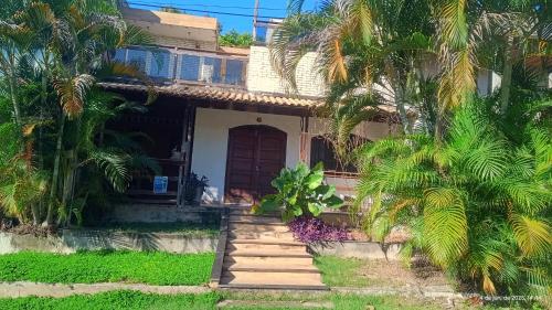 a house with palm trees in front of it at Casa Rústica com piscina,churrasqueira,banheira e ar condicionado in Senador Augusto Vasconcelos