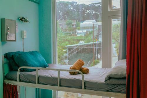 a small bed in a room with a window at Hugo's Family in Da Lat