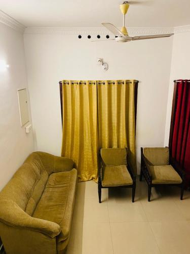 sala de estar con sofá y cortina amarilla en Comodita Residence, en Kochi