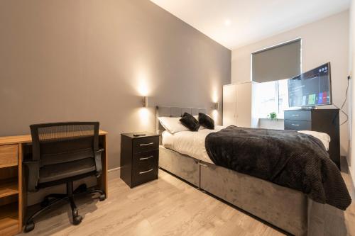 a bedroom with a bed and a desk and a television at 1 Bedroom Luxury Serviced Apartment in Bradford