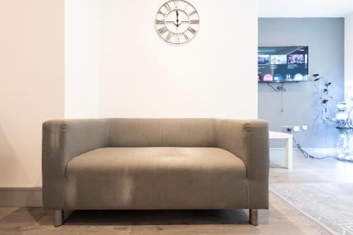 a chair in a living room with a clock on the wall at 1 Bedroom Luxury Serviced Apartment in Bradford