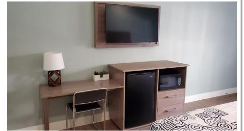 a room with a desk with a television on a wall at Crestridge Inn Near LAX, SoFi Stadium & Intuit Dome in Inglewood
