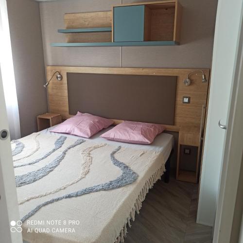 - une chambre avec un lit et 2 oreillers roses dans l'établissement Résidence Camping Les Dunes, au Grau-dʼAgde