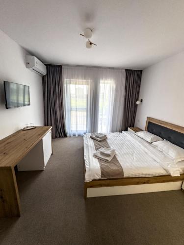 a bedroom with a bed and a desk and a window at Vila Marbo in Baile Felix
