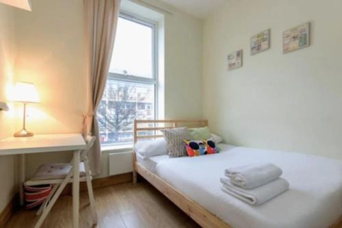 a bedroom with a bed and a desk and a window at Portobello Rooms by PrimeCityHosts in London