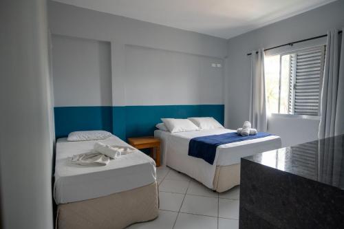 a bedroom with two beds and a window at Pousada La Naila in Bertioga