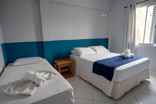 a bedroom with two beds and a window at Pousada La Naila in Bertioga