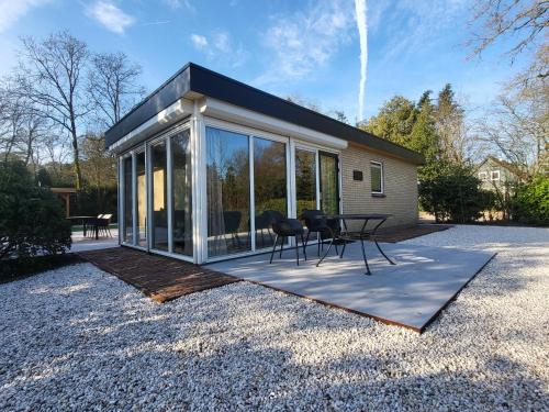 a house with glass doors and a table and chairs at Boshuisje Seth sauna en whirlpool in Appelscha