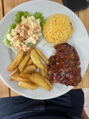 a white plate of food with meat and french fries at Hotel Estadio Real in Medellín