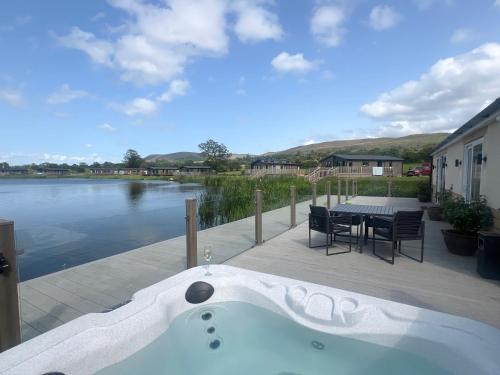 a bath tub sitting on a deck next to a lake at Luxurious and Peaceful Lakeside House, Clitheroe in Clitheroe