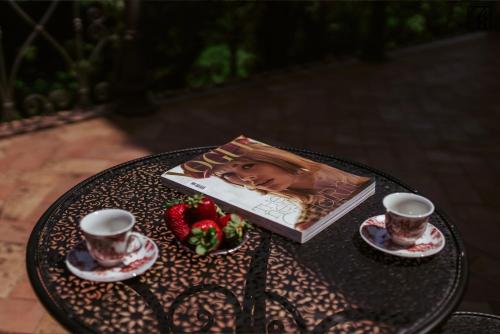 a book on a table with two cups and strawberries at Palazzo Rossi, Historic Boutique Home in Marche in Sarnano