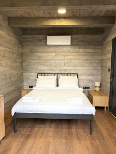 a bedroom with a white bed with a wooden wall at Slana bara glamping in Slana Bara