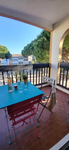 une table bleue et une chaise sur un balcon dans l'établissement Camargue Village 2 Clim Balcon, au Grau-du-Roi