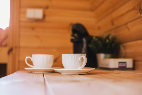 2 tasses de café blanches assises sur une table en bois dans l'établissement Tonneau en bois insolite au coeur du Charolais, à Baron