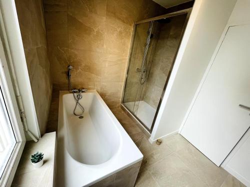 une salle de bain avec une baignoire blanche et une douche dans l'établissement Rêve bleu au port avec parking gratuit, à Caen