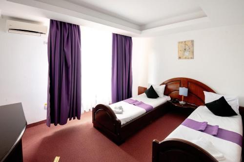 a hotel room with two beds and purple curtains at Royal by Euxin in Constanţa