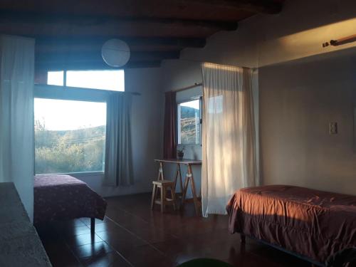 a bedroom with a bed and a window and a table at Departamento Los Horneritos in La Cumbre