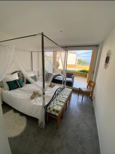 - une chambre avec un lit à baldaquin et un balcon dans l'établissement Serenity Apprt 1, à Théoule-sur-Mer