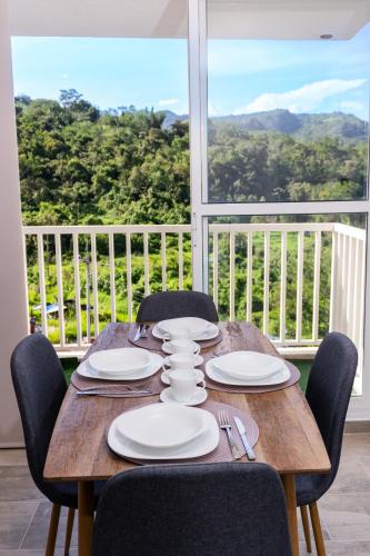 a wooden table with chairs and plates and a view at Villajesu Apartamento in Villeta