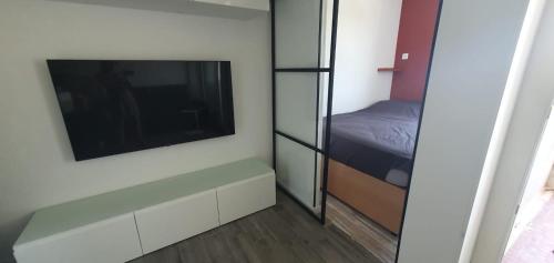 une petite chambre avec un lit et une télévision à écran plat dans l'établissement Studio rénové en 2025 à la marina, au Cap d'Agde