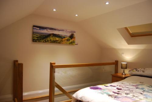een slaapkamer met een bed en een schilderij aan de muur bij Malvern Stables in Great Malvern