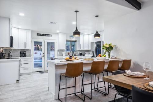 a kitchen with white cabinets and a table with chairs at Havasu Fun Stay Pool Spa PoolTable KingBed in Lake Havasu City