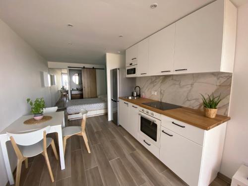 une cuisine avec des armoires blanches et une table et des chaises dans l'établissement Studio vue mer au Mont des Oiseaux à Hyères, à Hyères