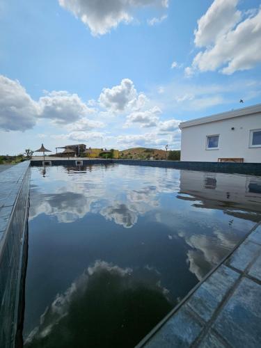 a pool of water with a building and clouds at Portugals Infinity - Fantástica casa de campo com vista de mar em Tavira in Tavira