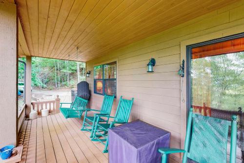 a porch with green chairs and a table on it at DJ Bear Den in Bryson City