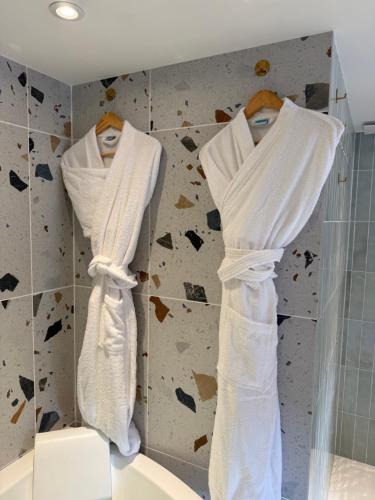 due asciugamani bianchi appesi a un muro in bagno di Dolcevita Suite - Signature italienne avec spa et filet a Saint-Étienne