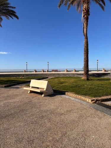 a bench sitting on the side of a road next to a palm tree at Domus Marina - Ionio room in Mondragone