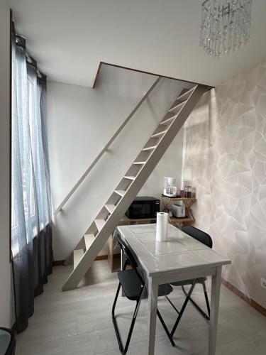 une table et des chaises dans une pièce avec un escalier dans l'établissement Appartement Mers Les Bains, à Mers-les-Bains