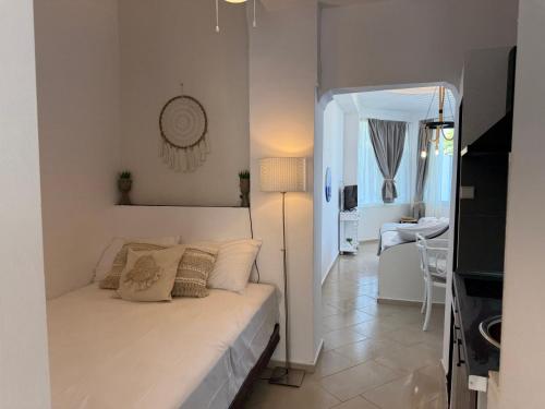 a white bedroom with a bed and a living room at Amelia Seaview Apartments & Studios in Kallithea Halkidikis