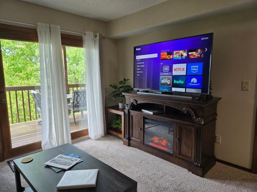 a living room with a flat screen tv and a fireplace at Swan's Woodland Getaway Condo in Reeds Spring