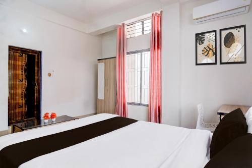 a bedroom with a white bed and a window at Hotel O Aradhyaa Inn in Dispur