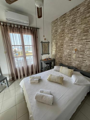 a large white bed in a room with a brick wall at Panagiotis Rooms in Naousa