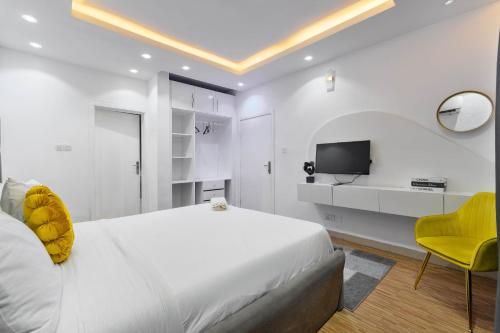 a white bedroom with a bed and a yellow chair at WATER VIEW 3 BEDROOM APARTMENT WITH JACUZZI PARKING WiFi NETFLIX POOL in Lekki