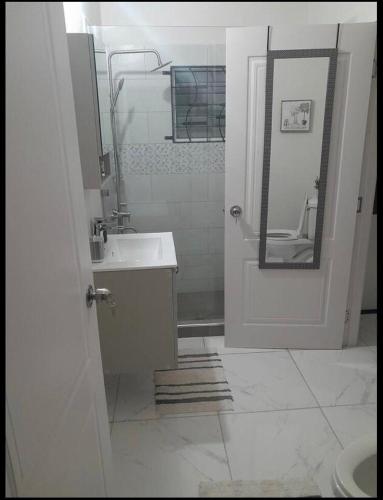 a white bathroom with a sink and a mirror at Phoenix park VD in Portmore