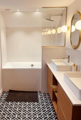 une salle de bain avec une baignoire, un lavabo et un miroir dans l'établissement Maison Yodée, à Cancale