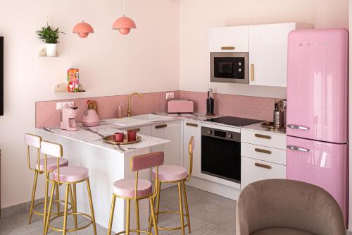 une cuisine avec un réfrigérateur rose et des tabourets de bar dans l'établissement Rosa Vida - Retro Chic, à Cannes