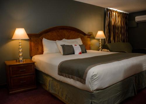 a hotel room with a large bed with two lamps at Ramada by Wyndham Medicine Hat in Medicine Hat