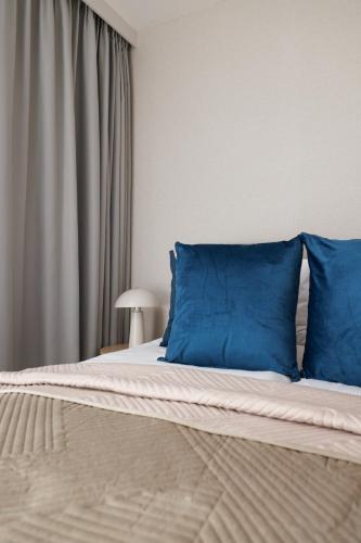 a bed with blue pillows in a bedroom at Rezydencja Merwede Aparthotel - My Rest in Gdańsk