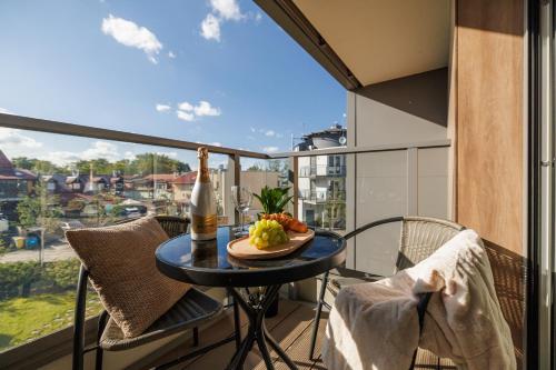 a table with a bottle of wine and fruit on a balcony at Rezydencja Merwede Aparthotel - My Rest in Gdańsk