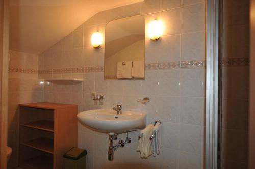 ein Bad mit einem Waschbecken und einem Spiegel in der Unterkunft Frühstückspension & Appartements Eugenie in Kitzbühel