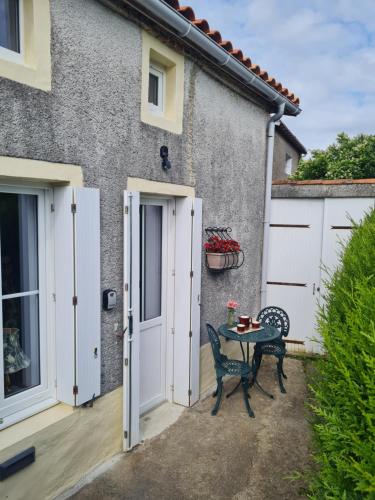 a patio with a table and chairs in front of a house at Le Petit Gite du Roy in Courlay