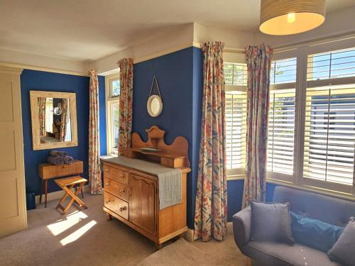 a living room with blue walls and a wooden dresser at Prospect Cottage in Hythe